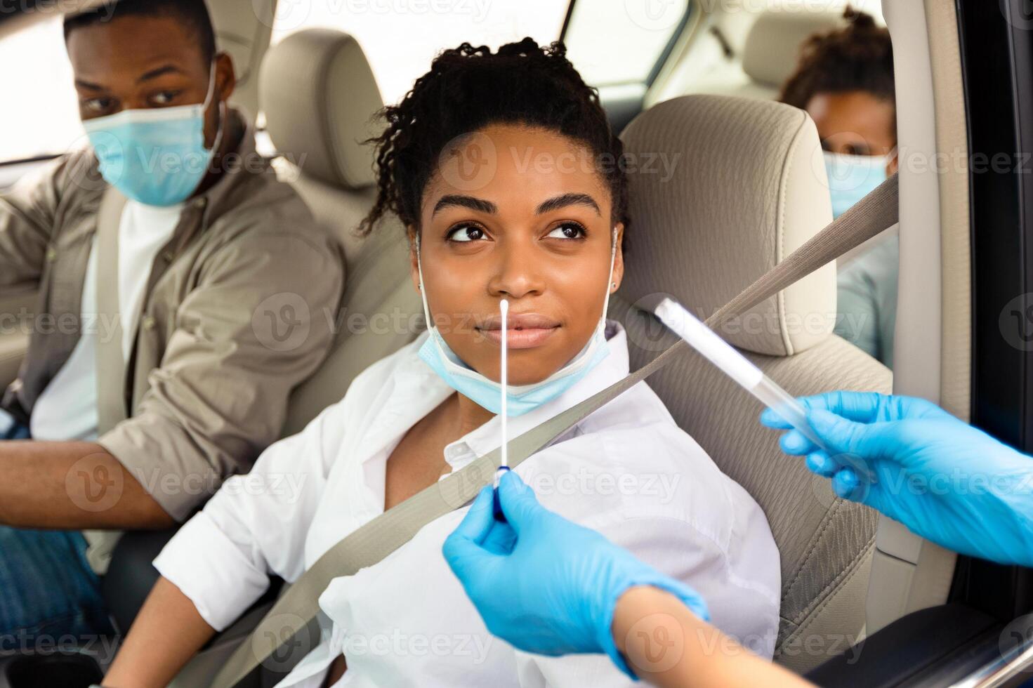 Covid-19 Diagnostic. Black Family Of Three Getting Tested For Coronavirus With Nasal PCR Test Sitting In Automobile, Wearing Protective Face Masks. Covid Pandemic Outbreak Concept photo
