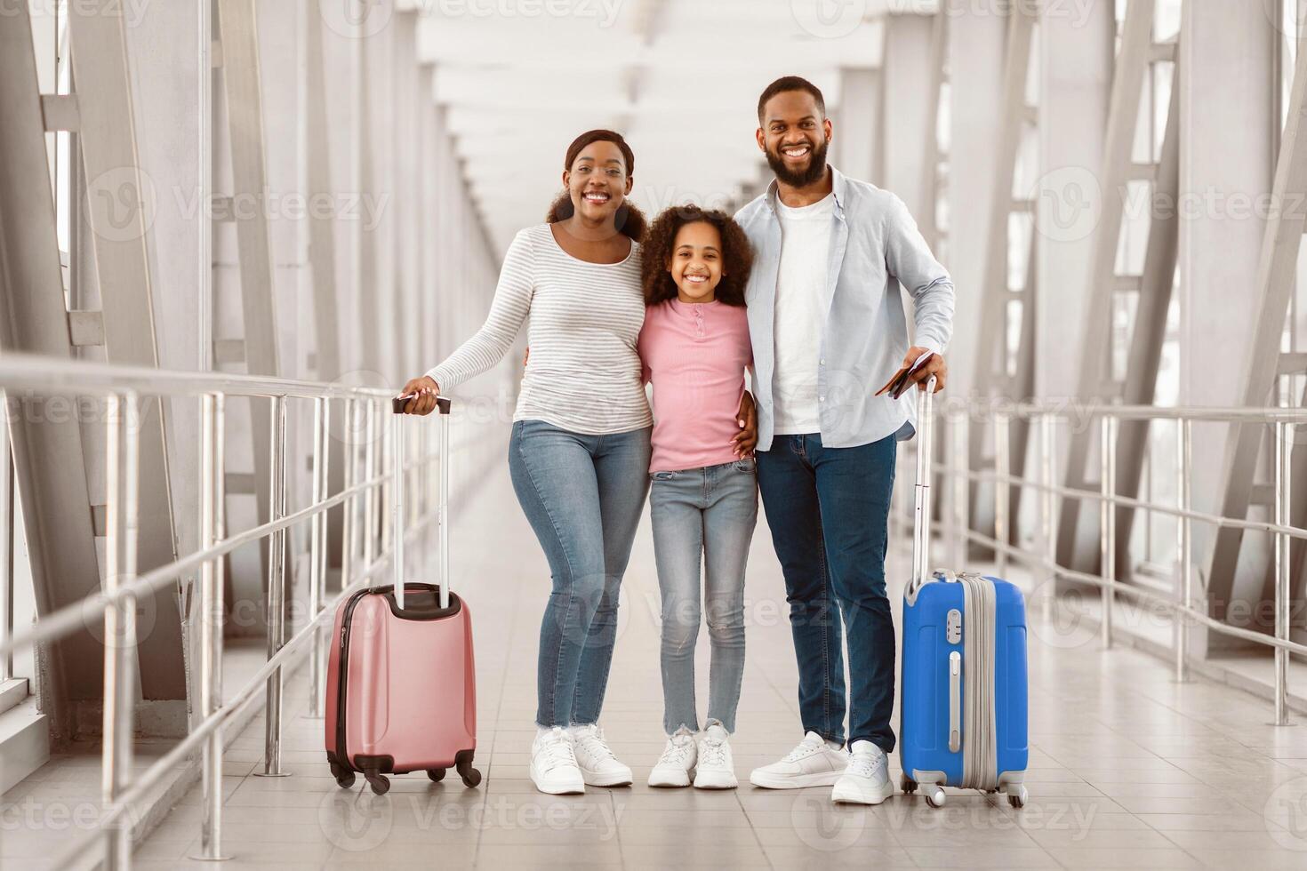 Traveling With Family. Full Body Length Of Cheerful African American People Standing In Airport Terminal, Holding Suitcases, Passports And Tickets, Posing And Looking At Camera Waiting For Departure photo