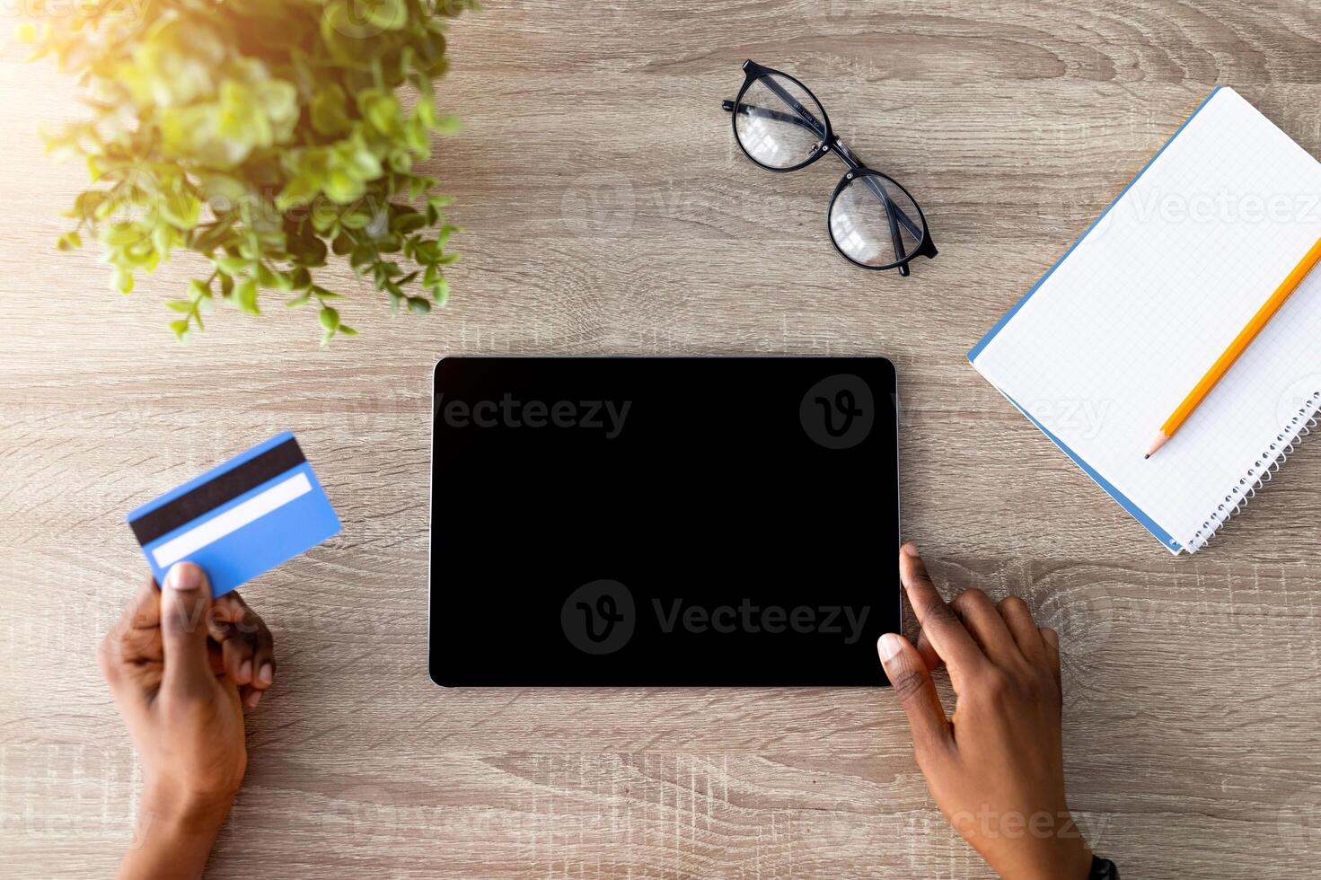 Top view of Afro lady with credit card using tablet pc for online shopping at wooden table, mockup for website or app. Millennial black woman ordering goods on touch pad, making contactless payment photo