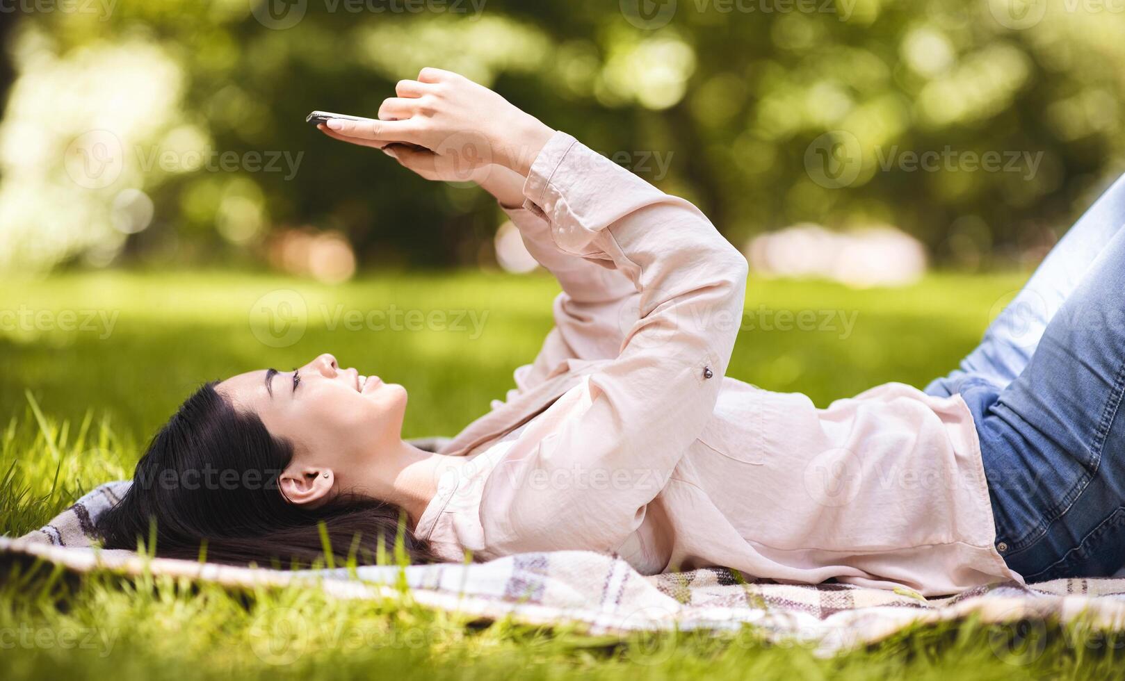 Young Korean Girl Relaxing With Smartphone Outdoors, Browsing Social Media, Using Free Wifi Spot In City Park, Side View photo