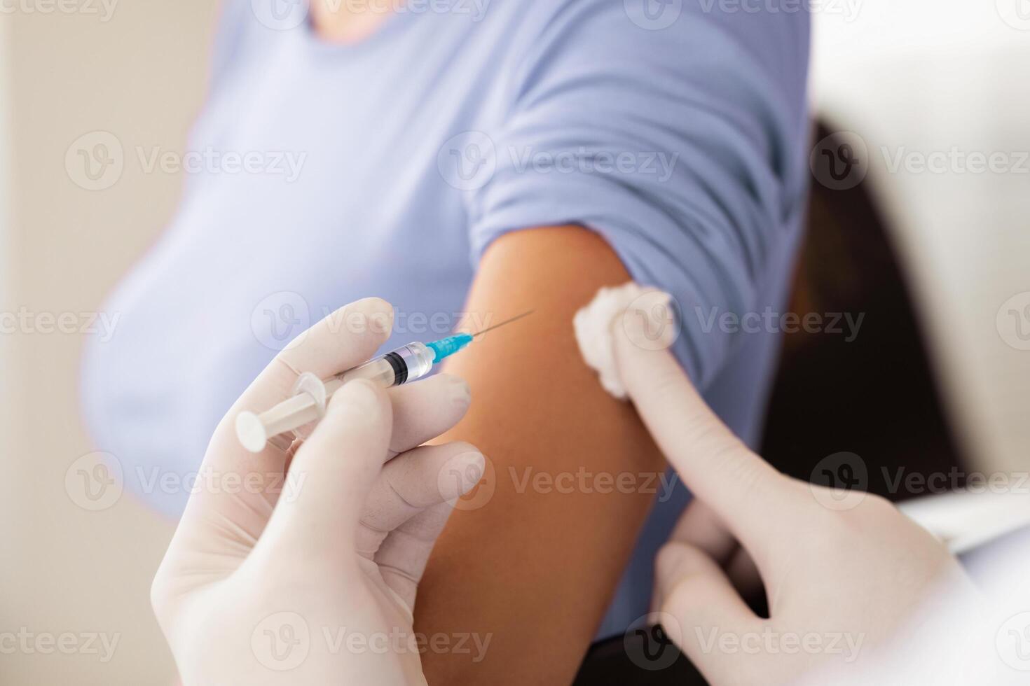 Closeup of doctor hands in protective gloves injecting vaccination in arm of unrecognizable female patient in clinic, cropped. Vaccination against COVID-19, healthcare and medical concept photo