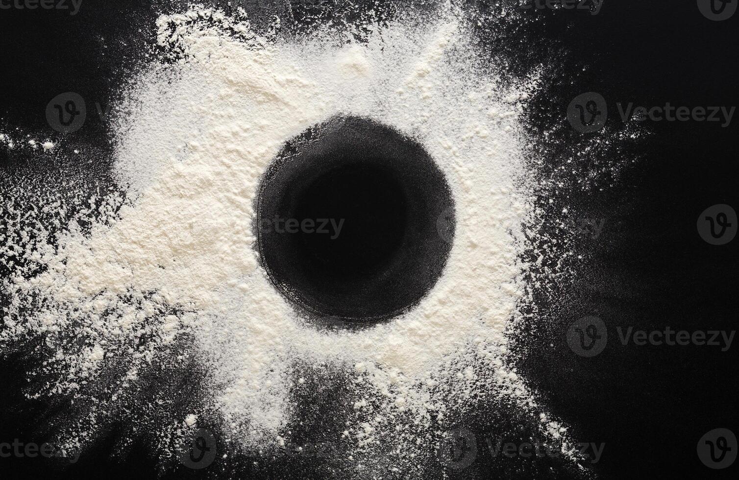 Abstract background. Sprinkled wheat flour circle, round spot on black. Top view on blackboard. Baking concept, cooking dough or pastry. photo