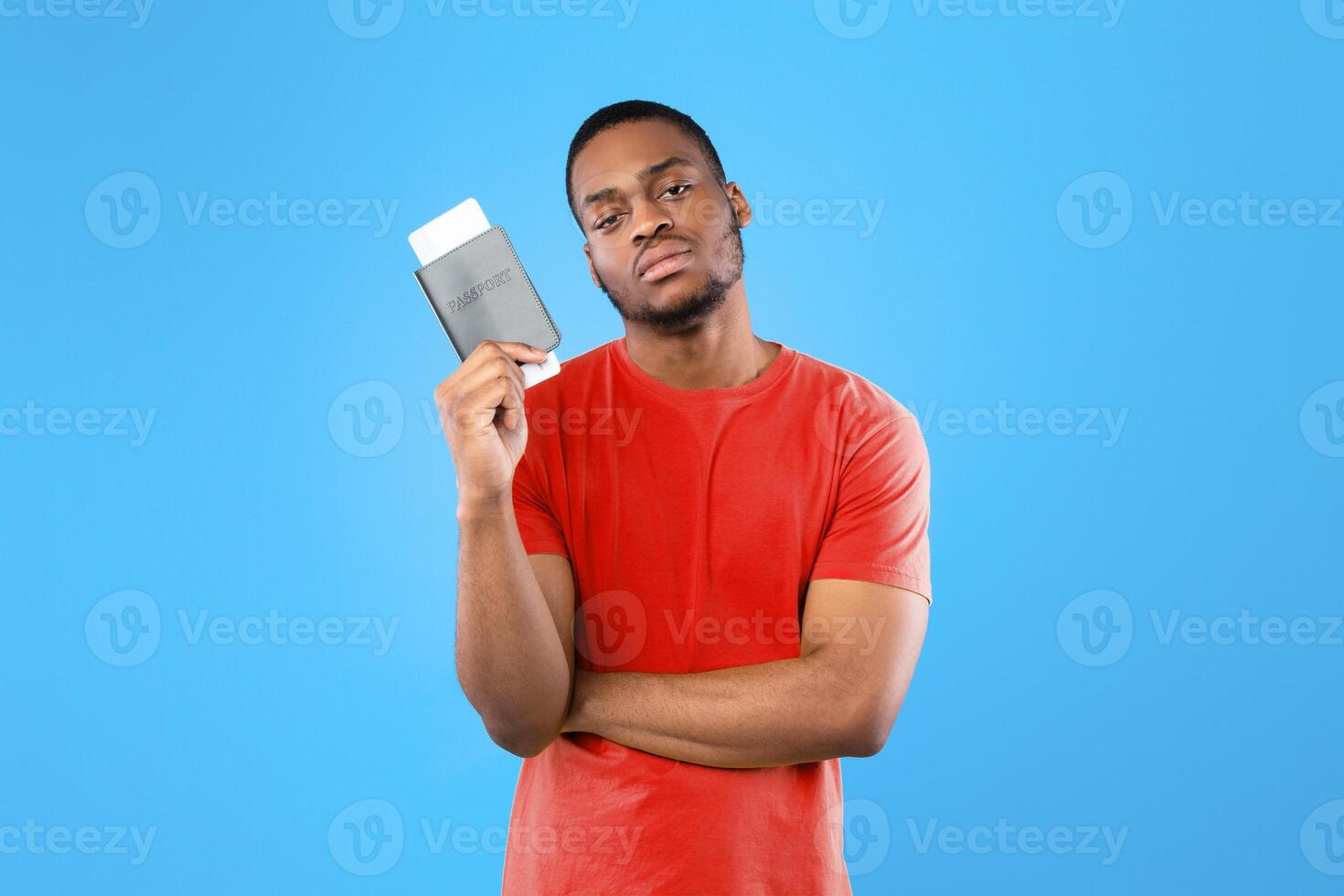 Cancelled Flight. Discontented Black Tourist Man Holding Travel Tickets Looking At Camera Posing Standing Over Blue Studio Background. Tourism And Traveling Difficulties During Pandemic Lockdown photo