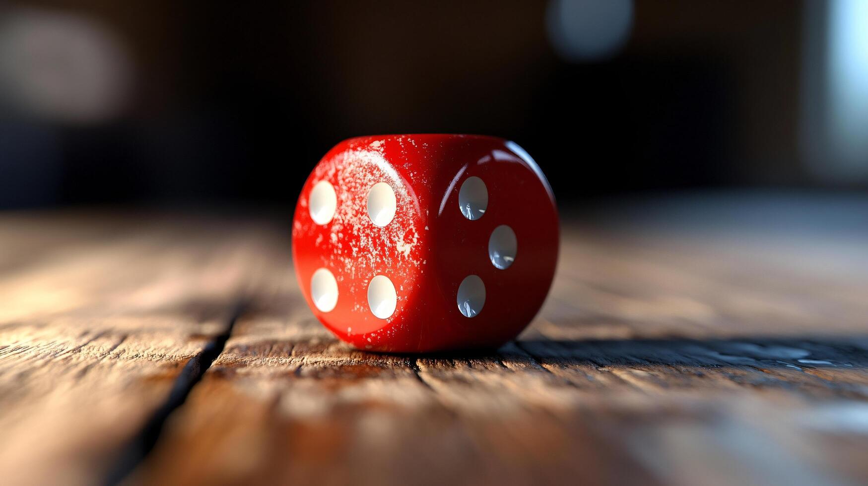 A red die sits on a wooden table photo