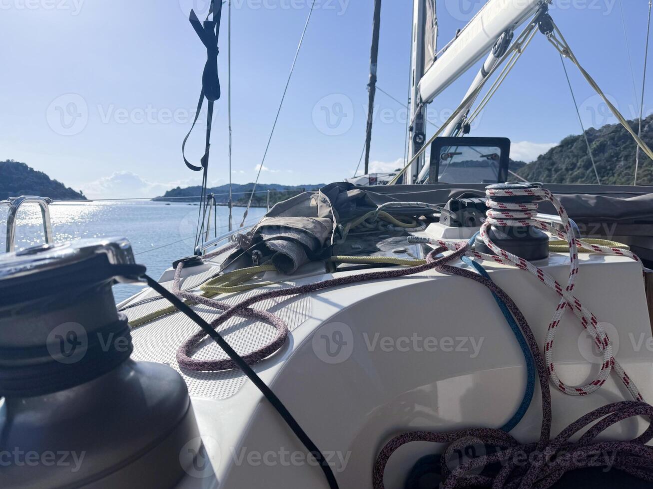 Sailboat navigating calm waters with ropes and gear on deck in bright daylight photo