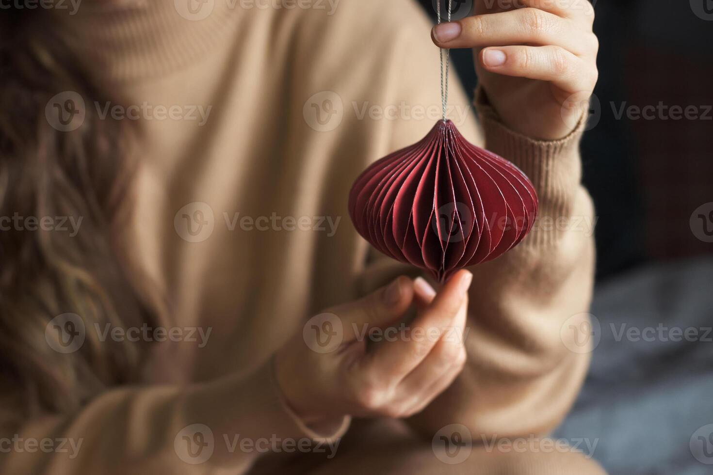 Woman holding a decorative ornament while sitting on a cozy bed during the festive season photo