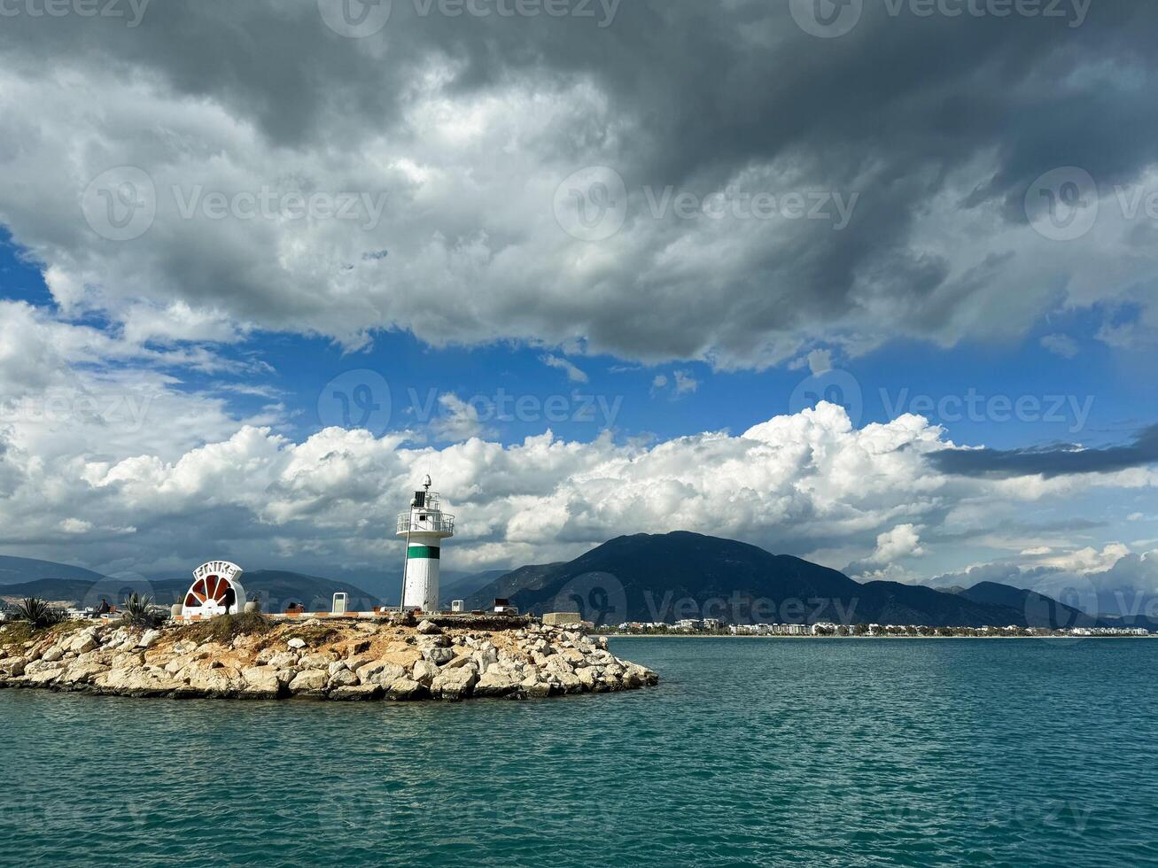 Scenic coastal view featuring a lighthouse and dramatic clouds over calm waters photo