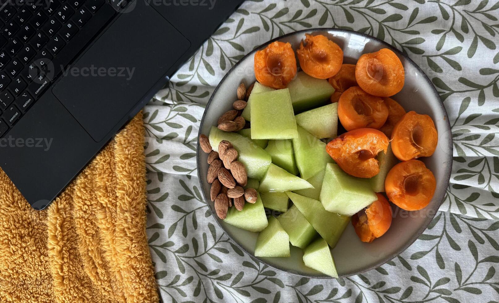 Fresh fruit and nuts breakfast spread on cozy blanket with laptop nearby photo