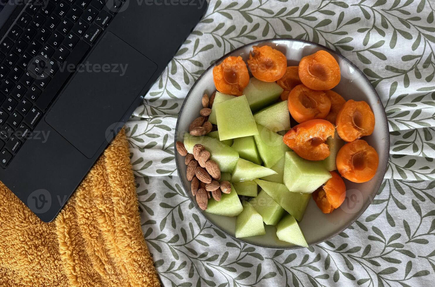 Fresh fruit platter on a cozy blanket beside a laptop in a relaxed setting photo