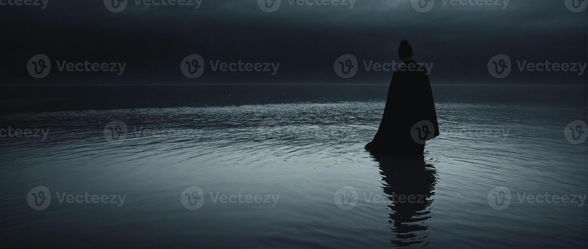 A man standing in the water with a dark sky photo