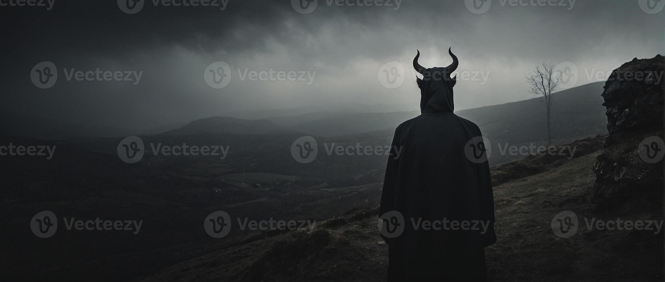 A man in a black cloak standing on a hill photo