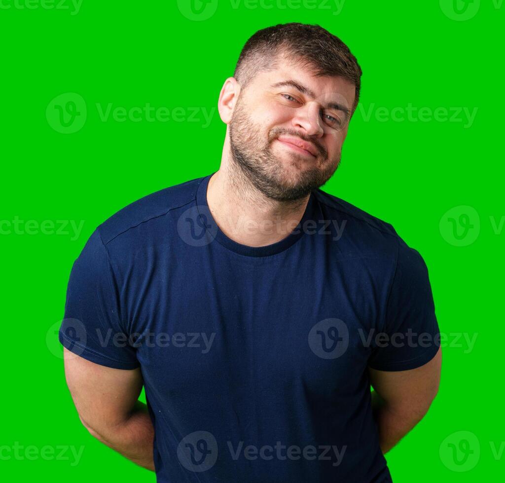 A young man smiles playfully against a bright green backdrop, showcasing a cheerful expression photo