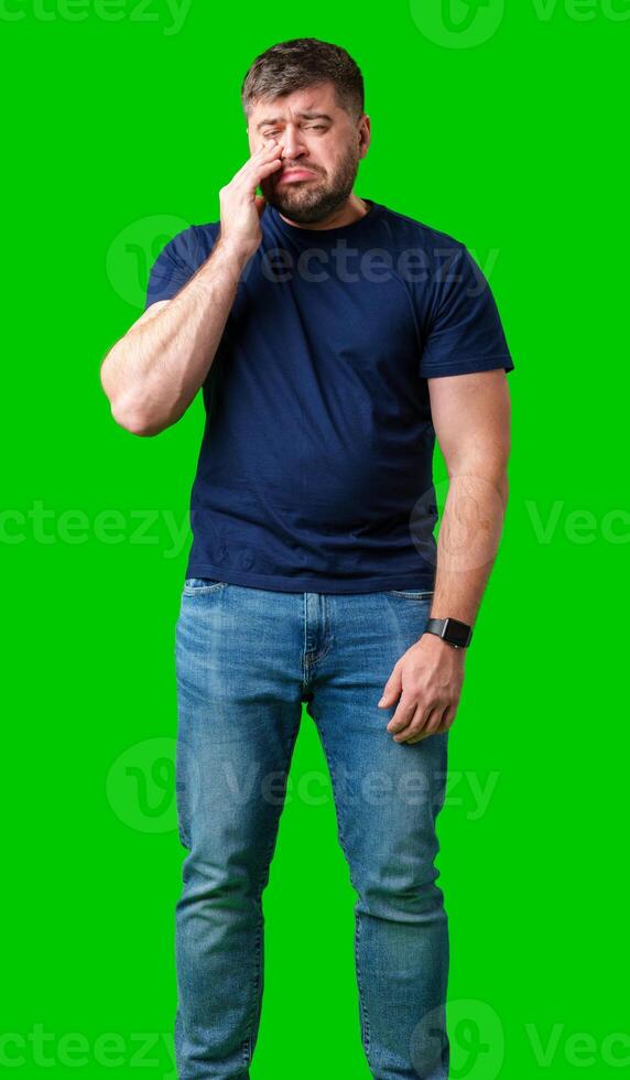 Man expressing frustration with tired eyes while standing in front of a bright green background photo