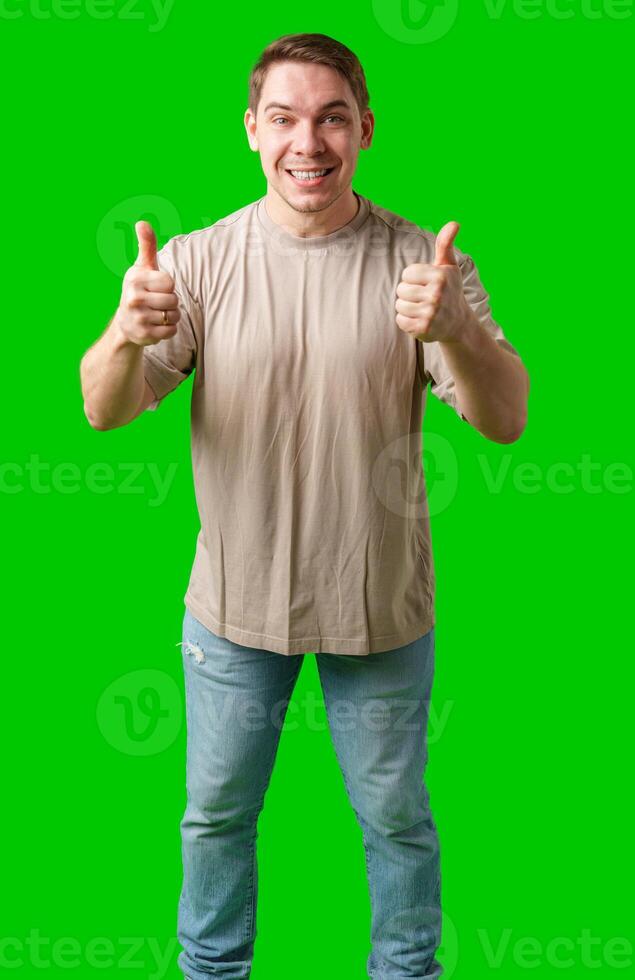 A man in a beige shirt gives a thumbs up while standing against a green background photo