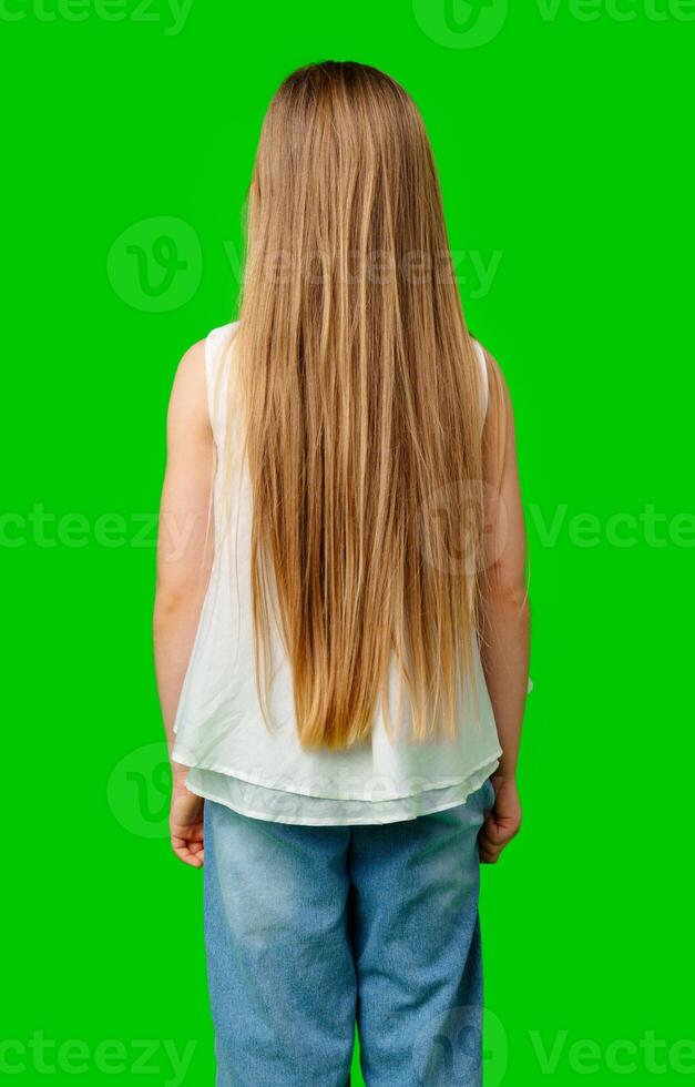 A young girl stands with her back to the viewer, showcasing her long, flowing hair photo