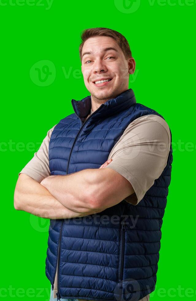Confident man in a navy vest and t-shirt poses with crossed arms against a bright green background photo