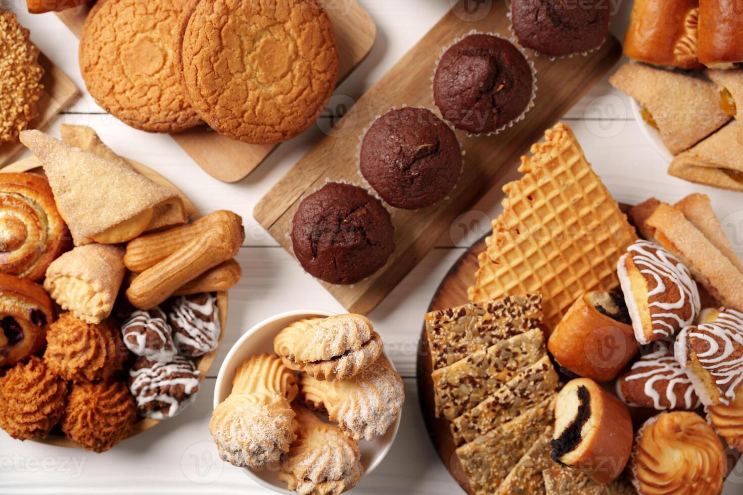 Assorted cookies and pastries displayed on wooden and ceramic trays at a dessert gathering photo