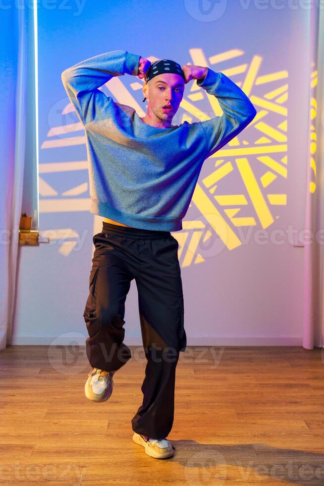 A young man dances in a studio with yellow light shining on the wall photo