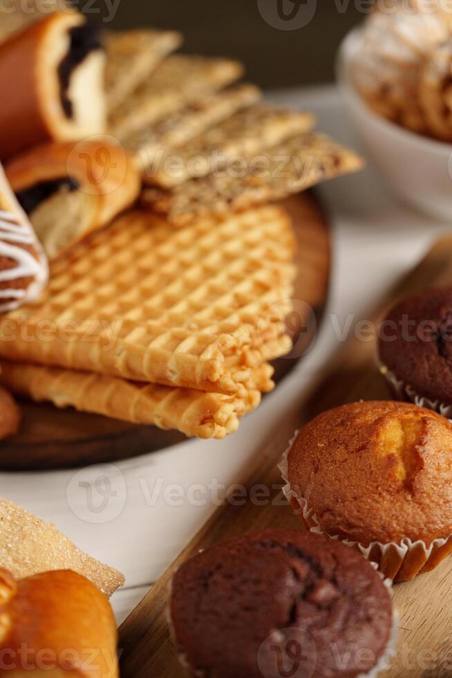Variety of baked treats displayed on a wooden board with a bowl of snacks at a cozy setting during the afternoon photo