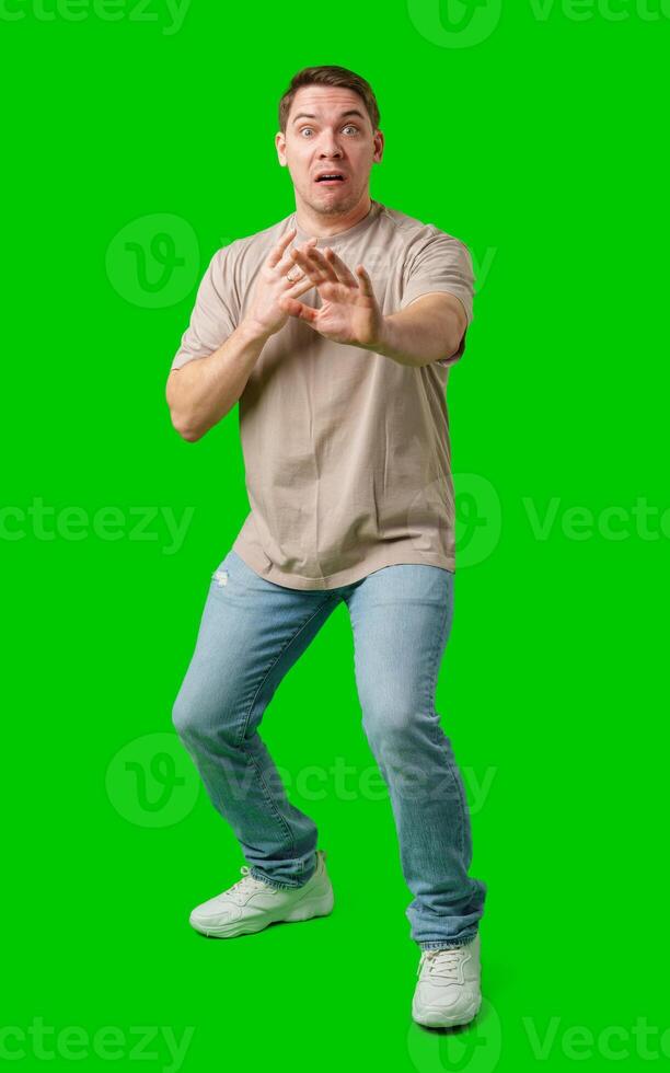Man expressing fear while standing against a bright green background photo