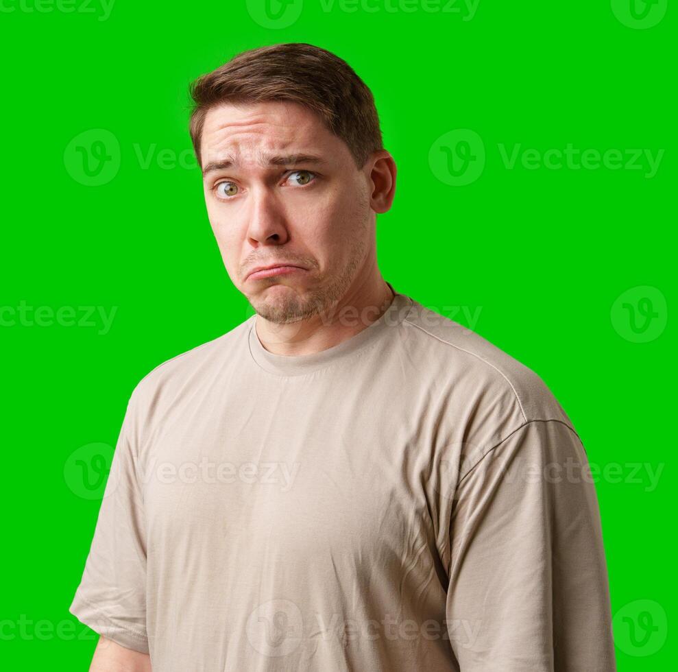 Man with a neutral expression poses against a bright green backdrop photo