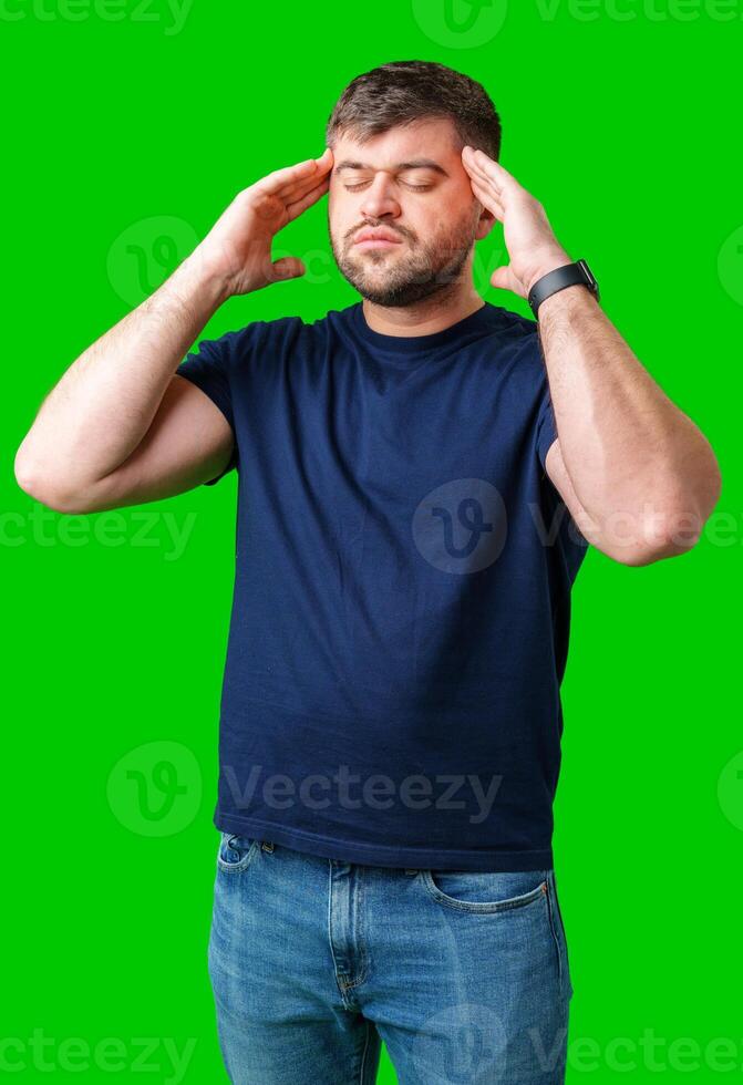A man with closed eyes holds his head in a thoughtful pose against a bright green backdrop photo