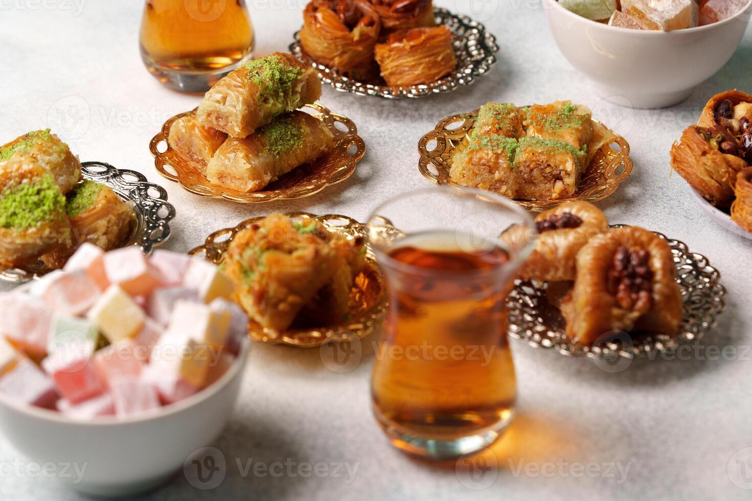 Traditional Middle Eastern sweets and tea served on decorative plates at a gathering photo