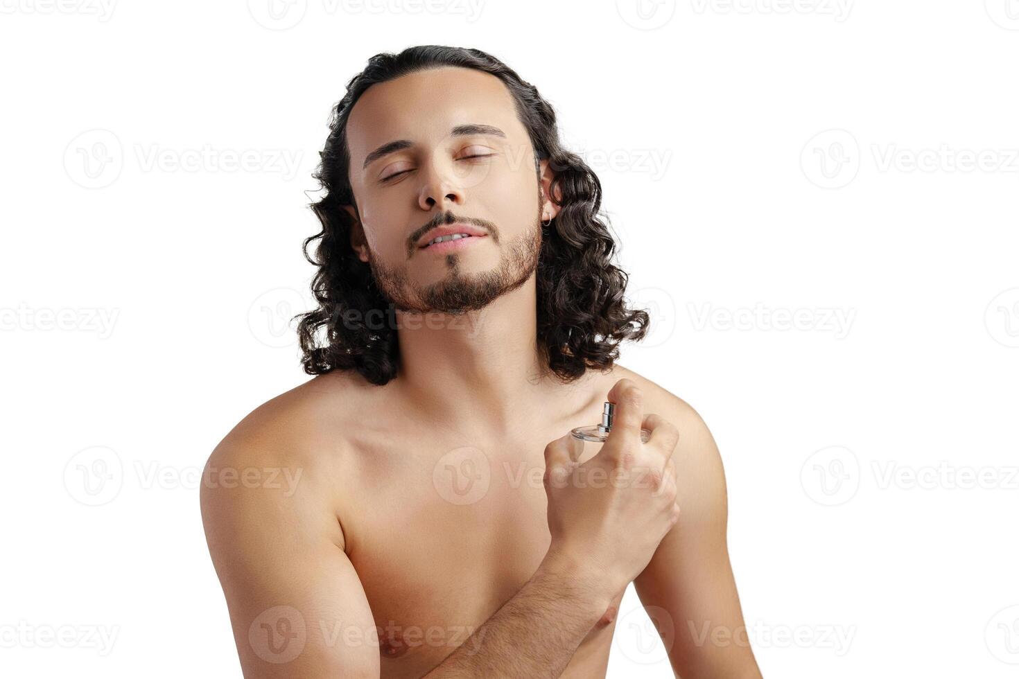 A young man with curly hair applying fragrance after a shower while smiling at the camera photo
