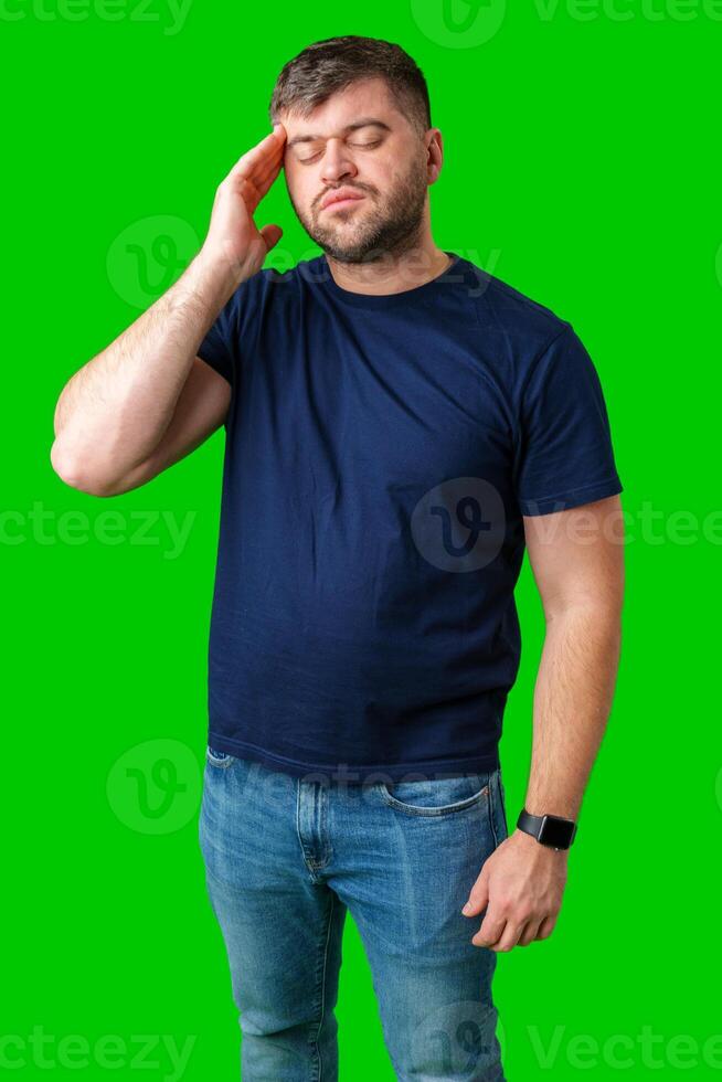 A man with closed eyes holds his head in a thoughtful pose against a bright green backdrop photo