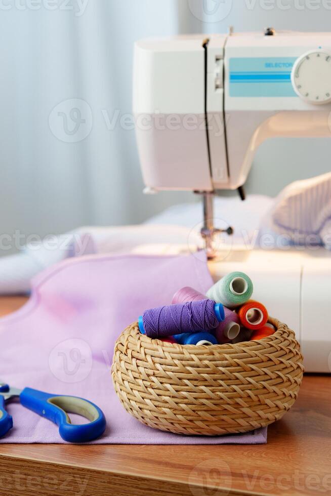 Sewing machine in use on a wooden table, stitching a light fabric in a well-lit indoor workspace photo