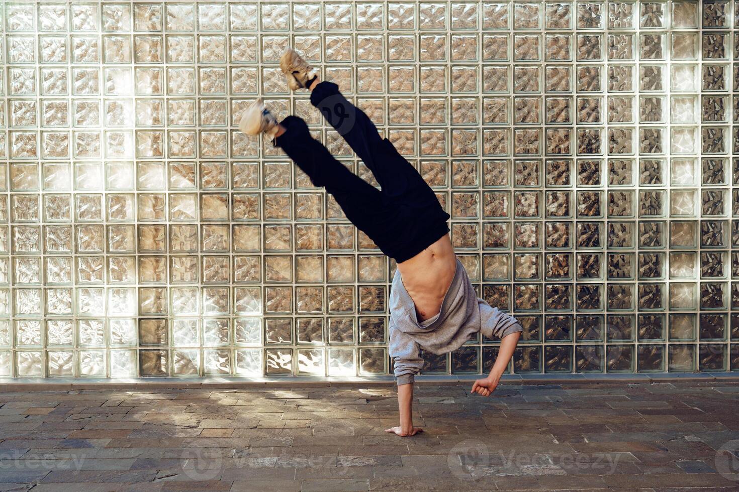 A young man performs a handstand in front of a brick wall photo