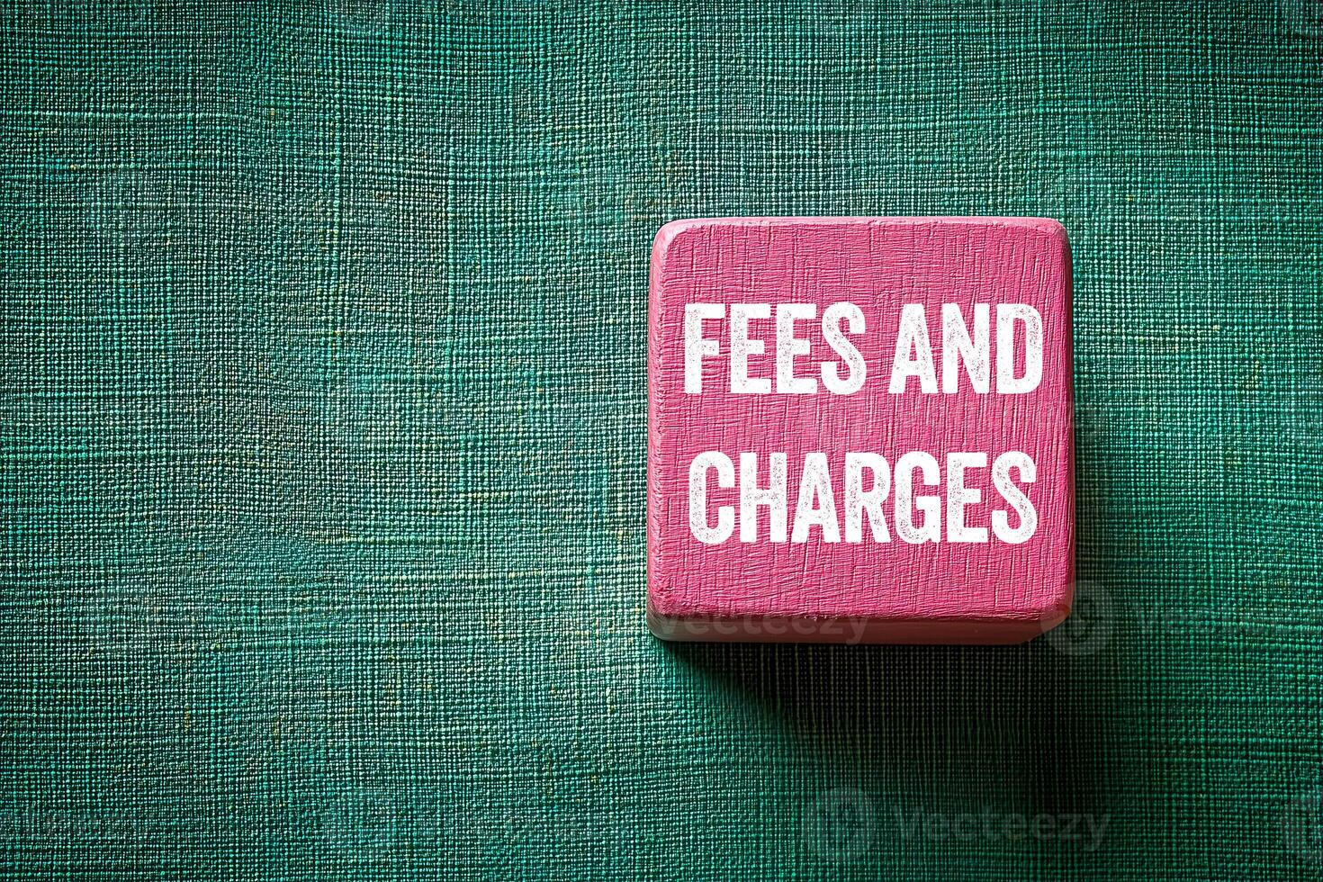 Fees and charges message written on pink wooden cube on green fabric background. Conceptual fees and charges symbol. Copy space. photo