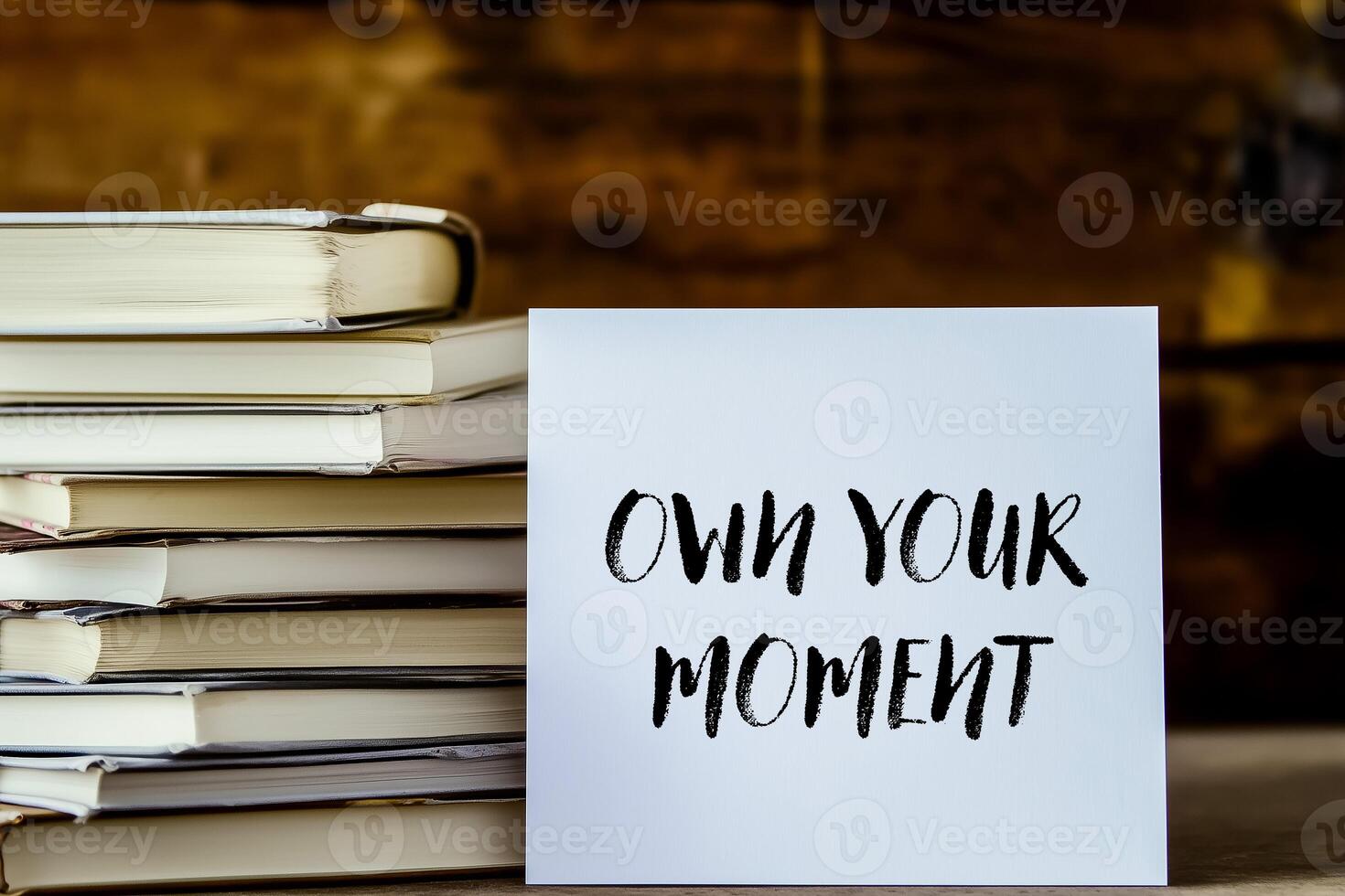 Own your moment message written on white card with stack of books photo