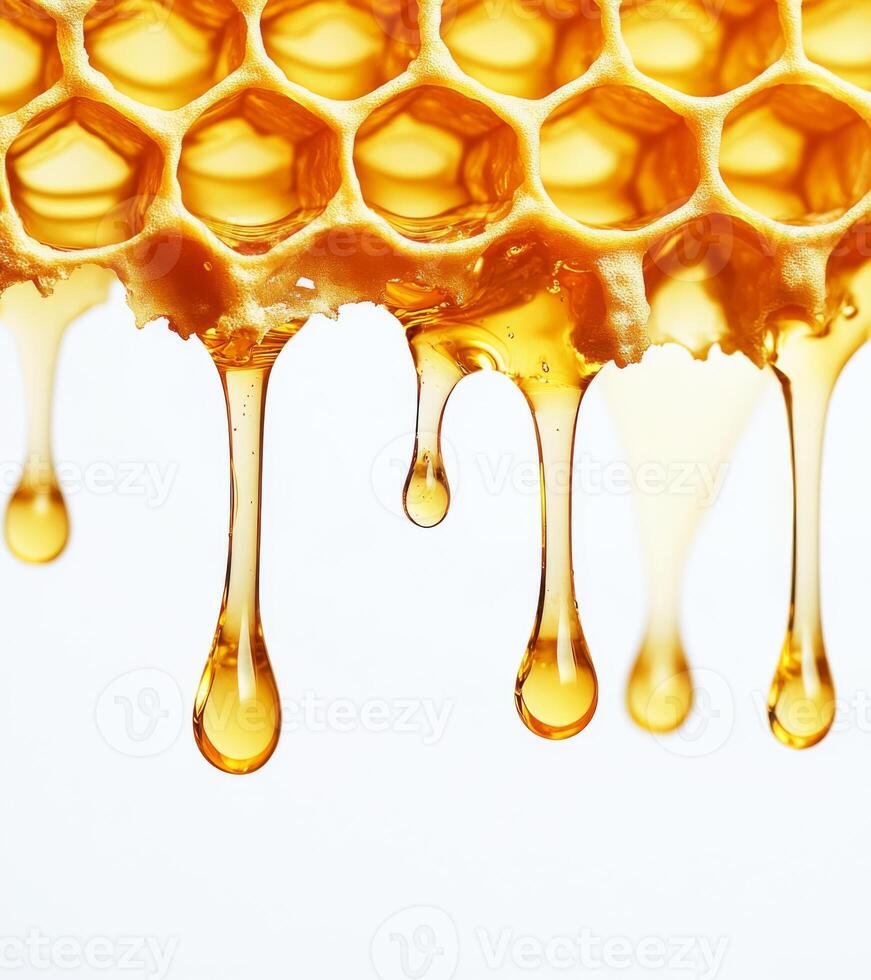 Golden honey drips from honeycomb against white background, showcasing natural sweetness and texture of honey. close up view highlights hexagonal pattern and rich, amber color photo