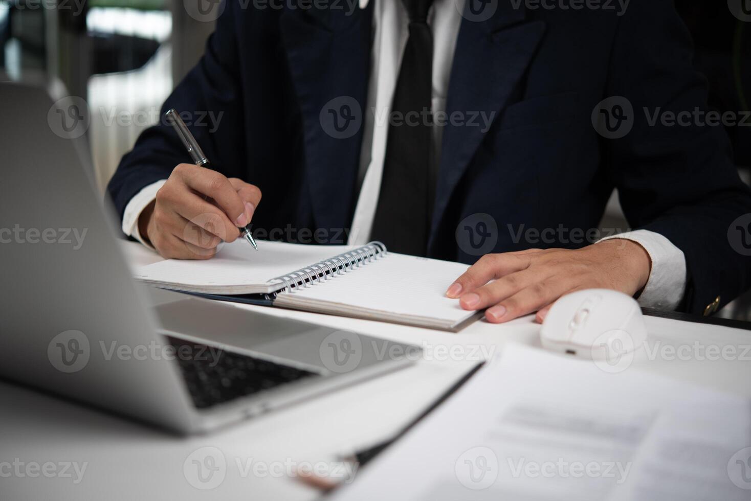 A man in a suit writing on a notepad photo