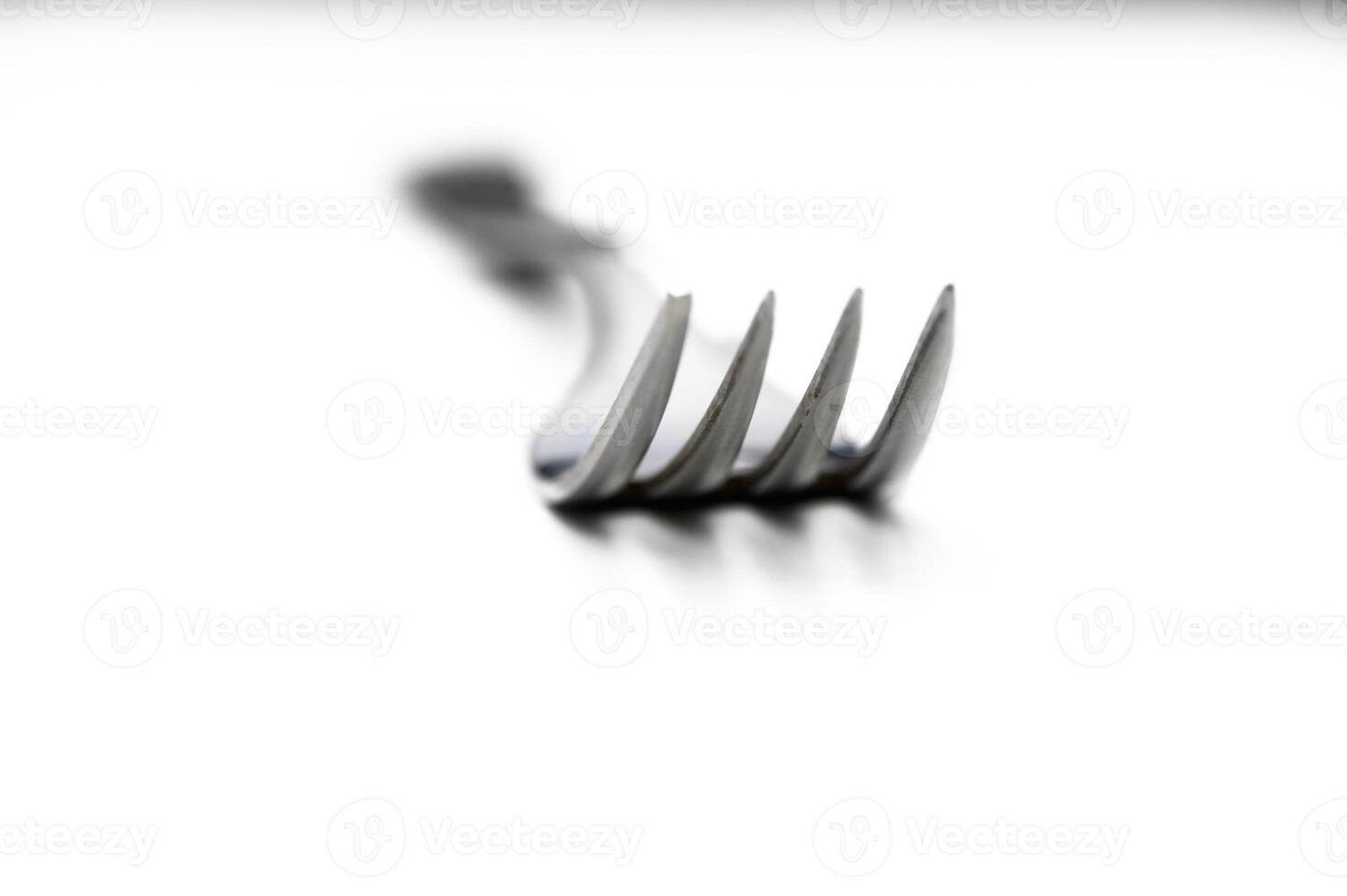 Close-up of a shiny fork resting on a white surface, creating a minimalist and artistic culinary focus photo