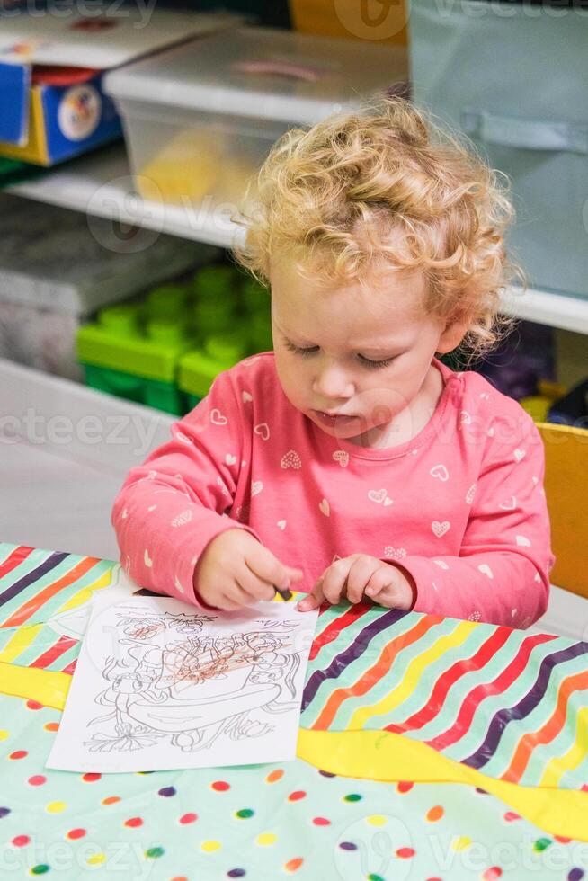 Beautiful blonde baby girl playing in kindergarten photo