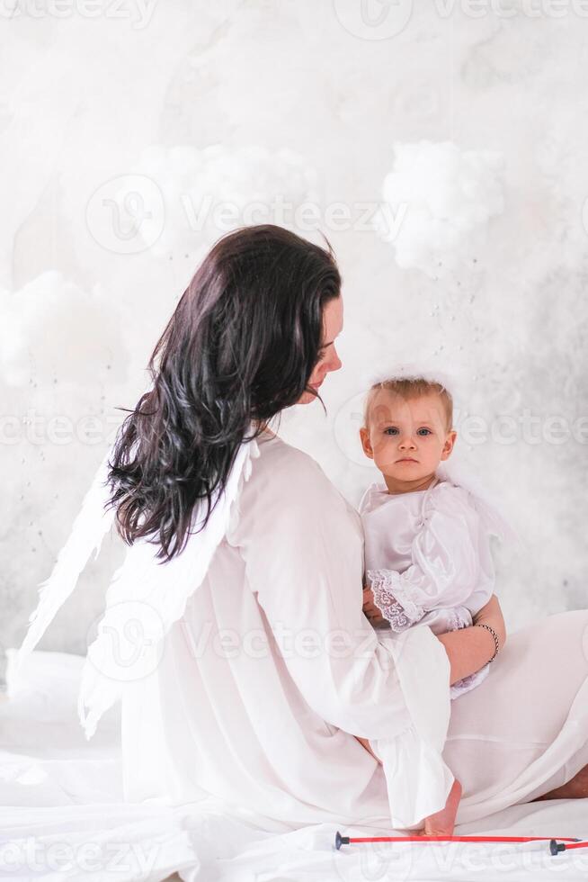 Beautiful mother and her toddler daughter wearing angel costumes photo