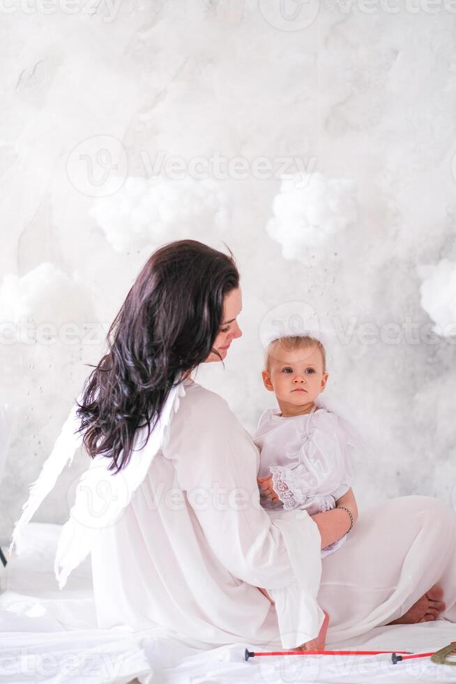 Beautiful mother and her toddler daughter wearing angel costumes photo