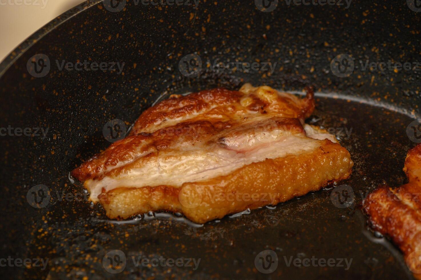 Sizzling pork belly being perfectly cooked in a hot skillet photo