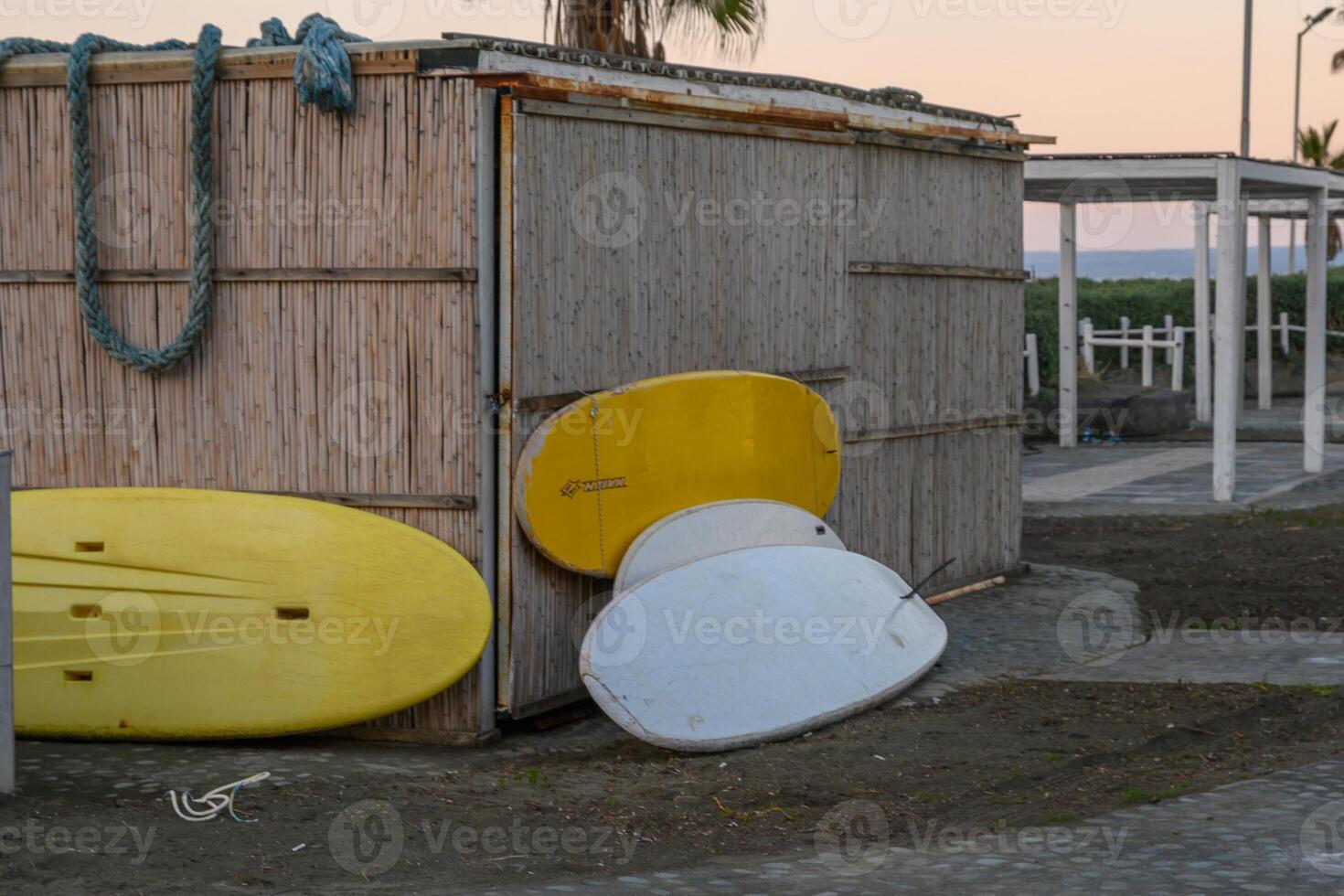 Colorful surfboards lean against a rustic beach shed at twilight by the ocean photo