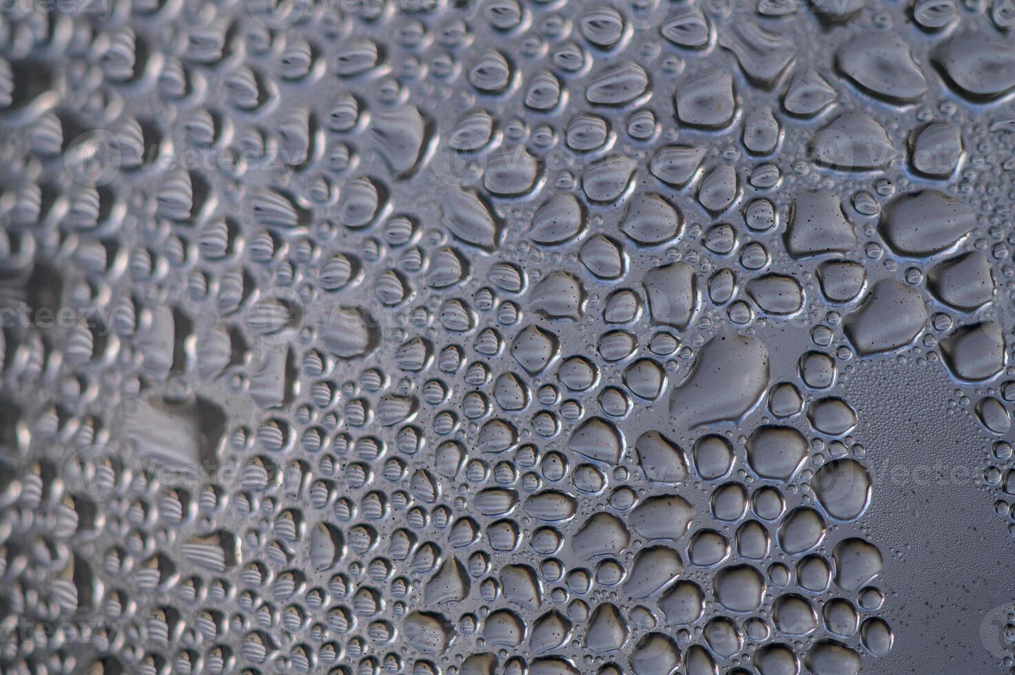 Raindrops gather on a window pane, creating a mesmerizing pattern of nature's artwork at dawn photo