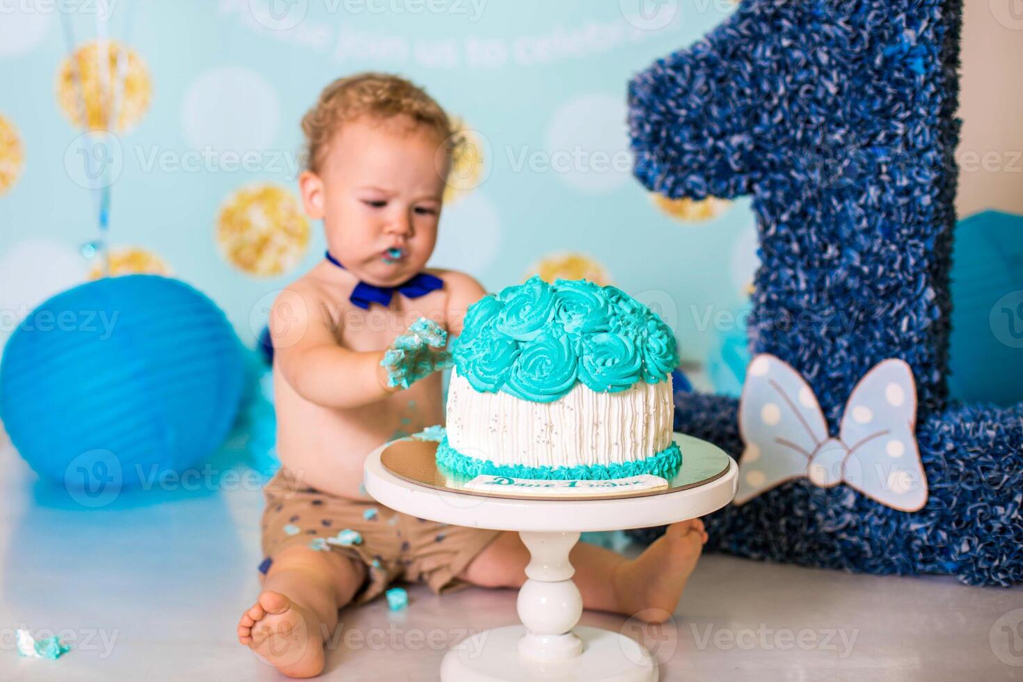 Baby boy playing with a cake during cake smash birthday party photo