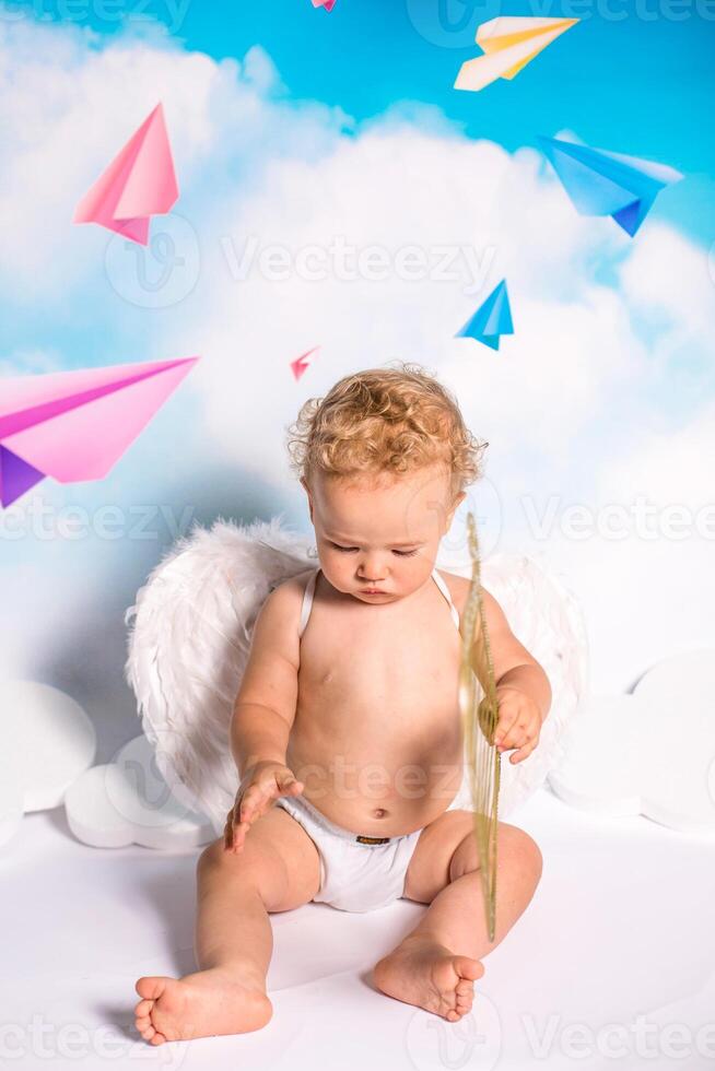 angel child is sitting the clouds looks down photo
