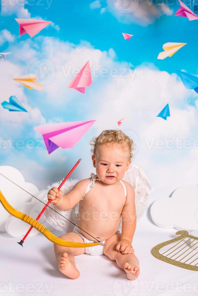 angel child is sitting the clouds looks down photo