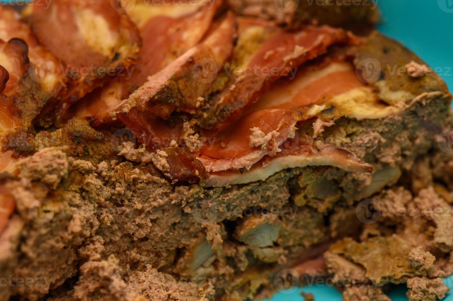 Savory meat pie adorned with crispy bacon served on a bright blue plate for a feast at home photo