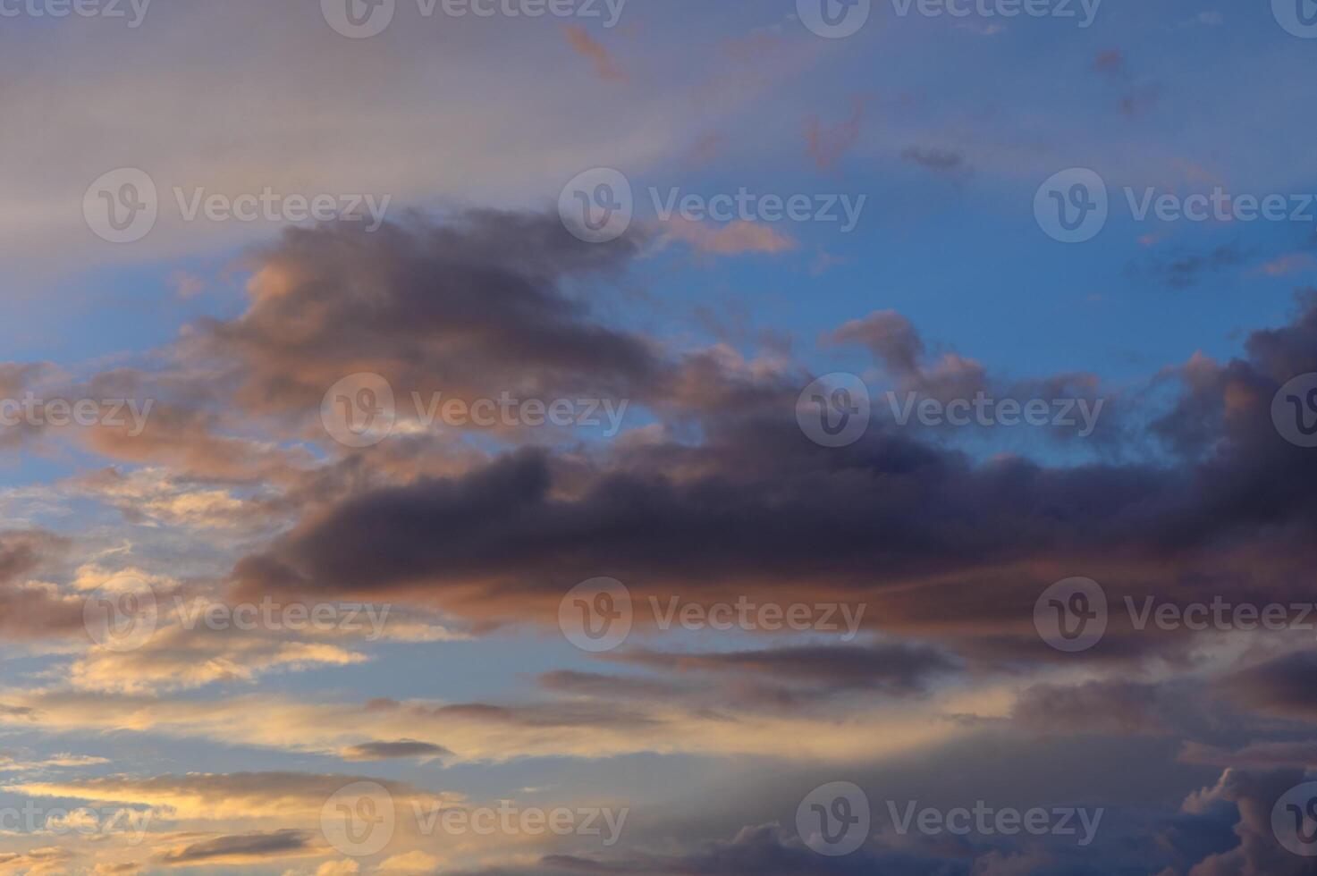 Dramatic evening sky filled with colorful clouds over a tranquil landscape at sunset photo
