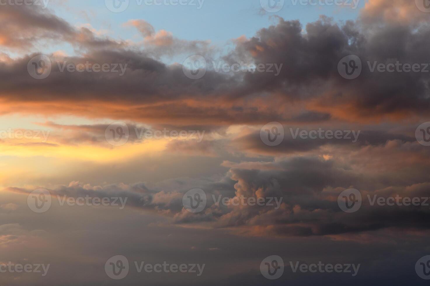 Vibrant sunset skies filled with dynamic clouds over a tranquil horizon photo