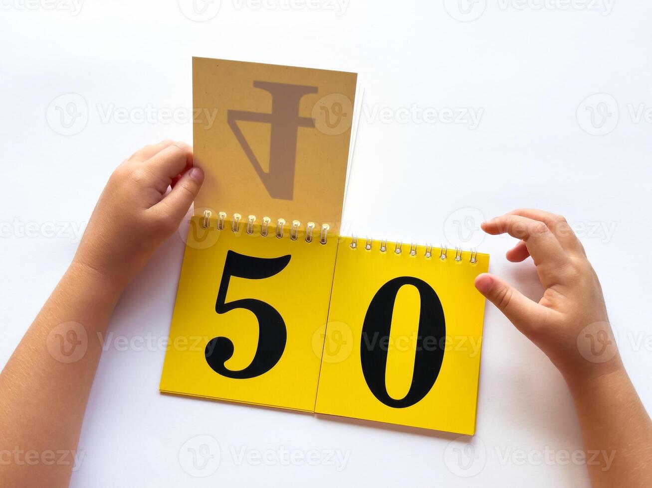 Childs hands flip through yellow pages with numbers. Displaying number 50 on white background photo