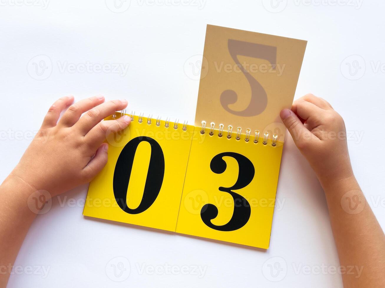 Childs hands holding flip calendar with number cards on white background photo